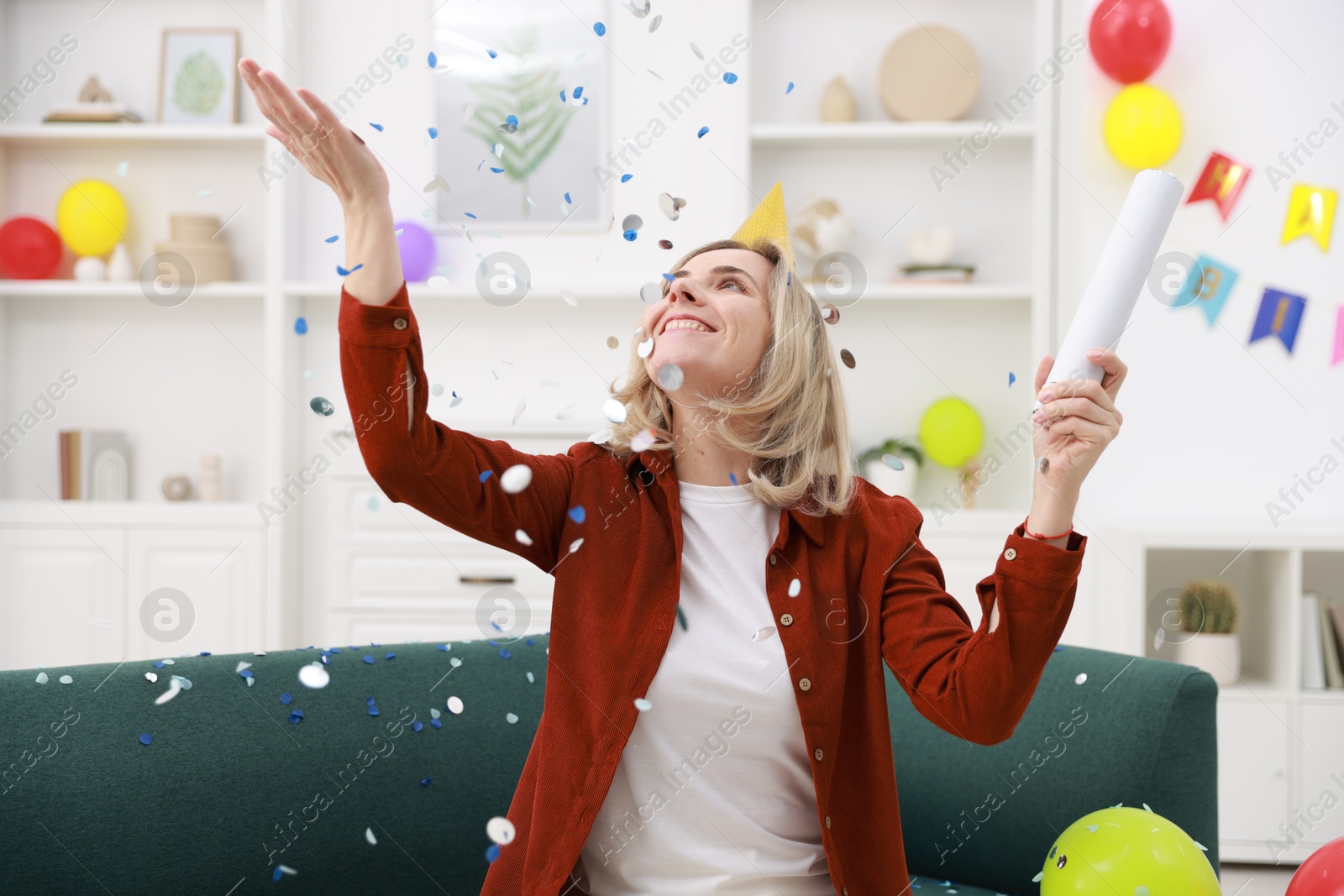 Photo of Happy woman with party popper and confetti in festive decorated room