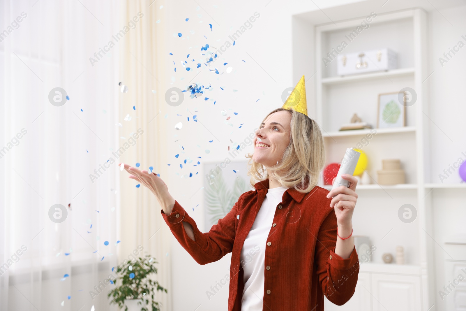 Photo of Happy woman with party popper and confetti in festive decorated room