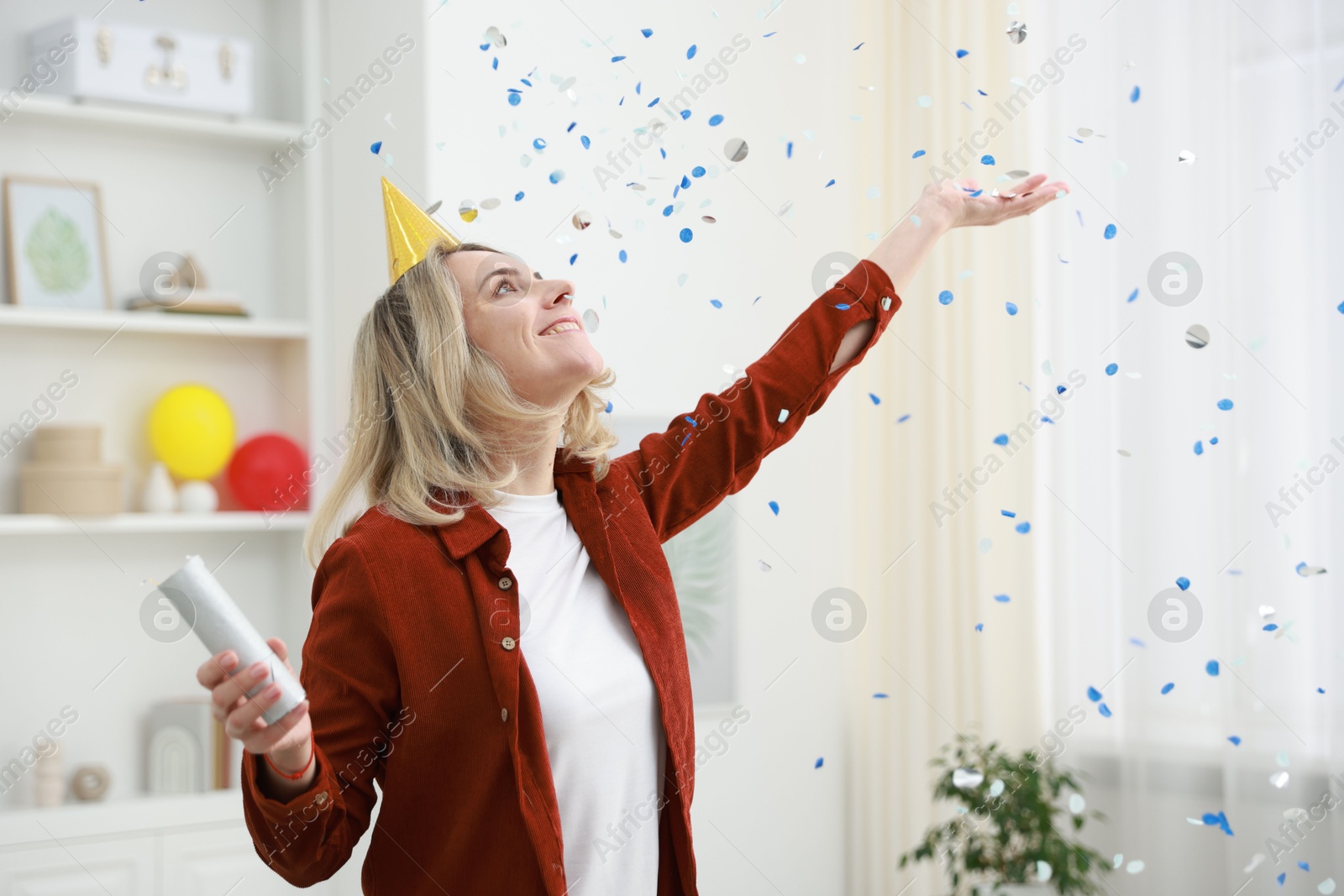 Photo of Happy woman with party popper and confetti in festive decorated room