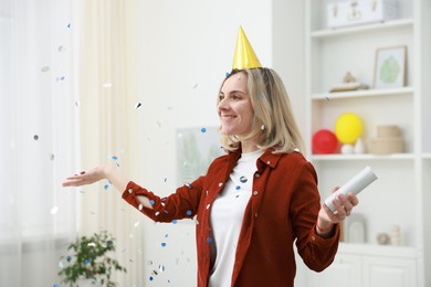 Photo of Happy woman with party popper and confetti in festive decorated room