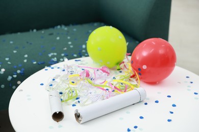 Photo of Confetti poppers, serpentine streamers and other party decor on white table indoors