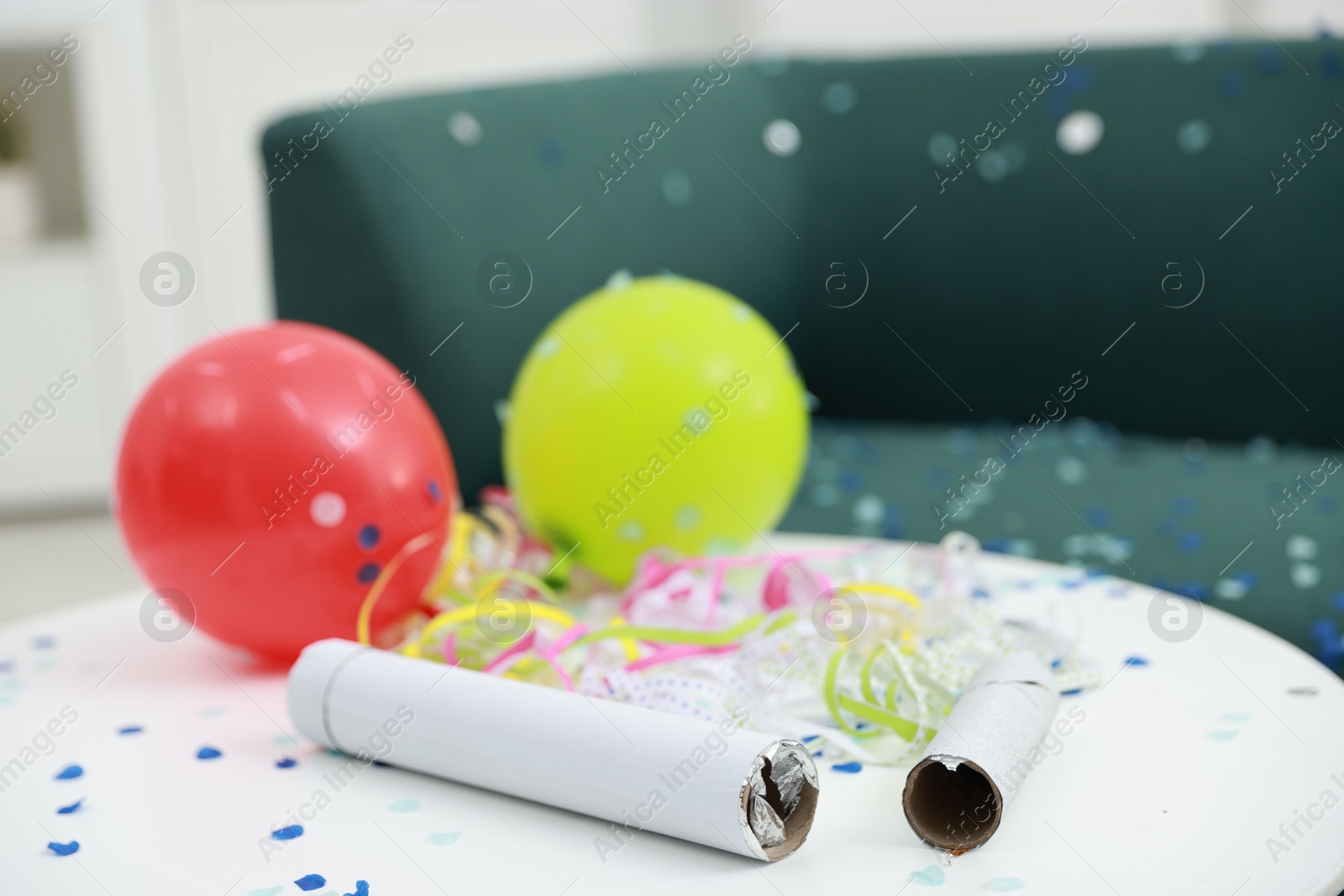 Photo of Confetti poppers, serpentine streamers and other party decor on white table indoors, closeup