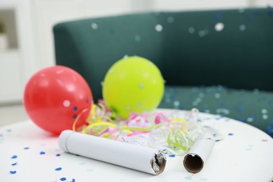 Photo of Confetti poppers, serpentine streamers and other party decor on white table indoors, closeup