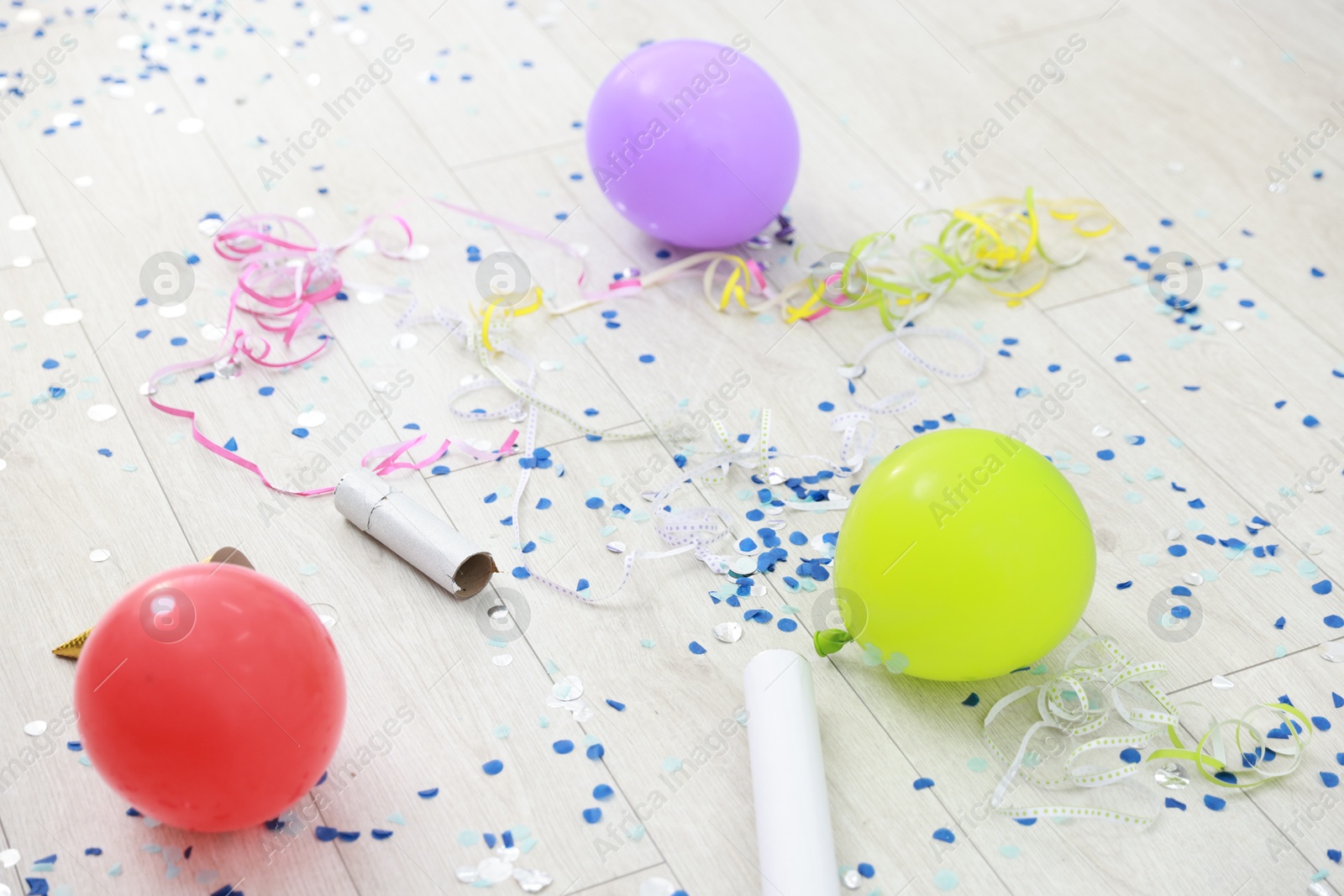 Photo of Confetti poppers, serpentine streamers and other party decor on floor indoors