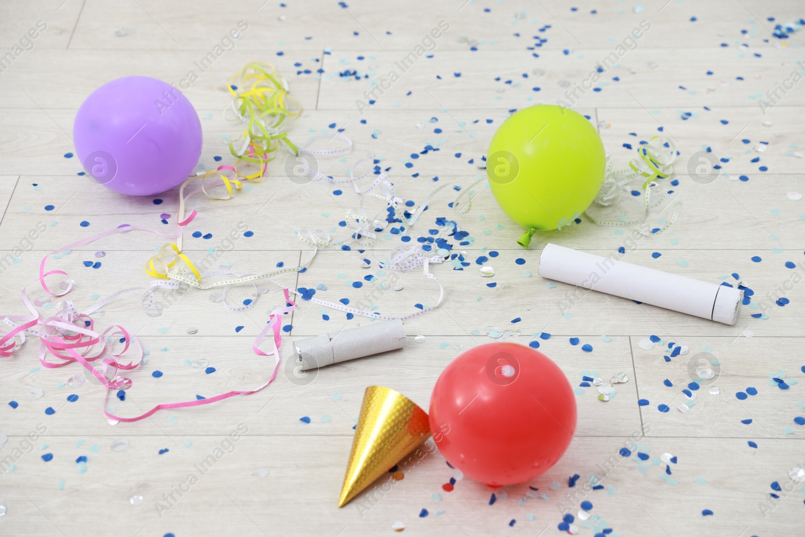 Photo of Confetti poppers, serpentine streamers and other party decor on floor indoors