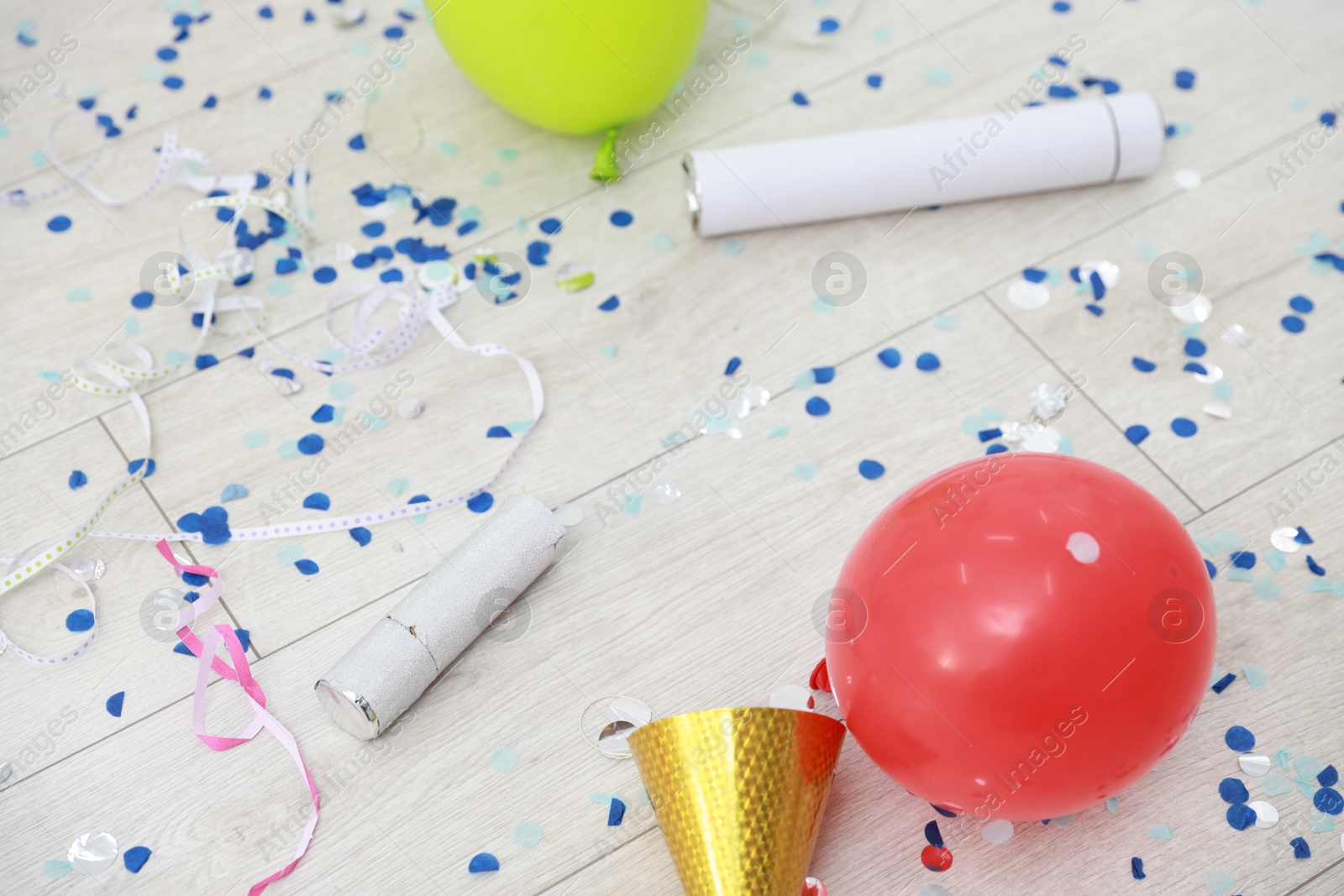 Photo of Confetti poppers, serpentine streamers and other party decor on floor indoors