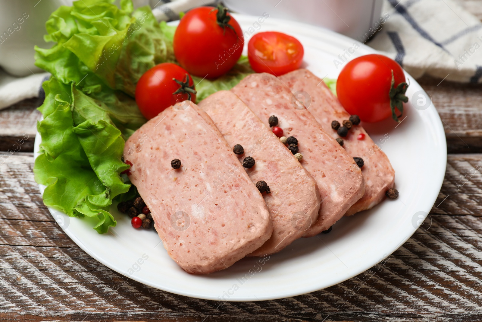 Photo of Tasty canned meat, tomatoes, lettuce and spices on wooden table, closeup