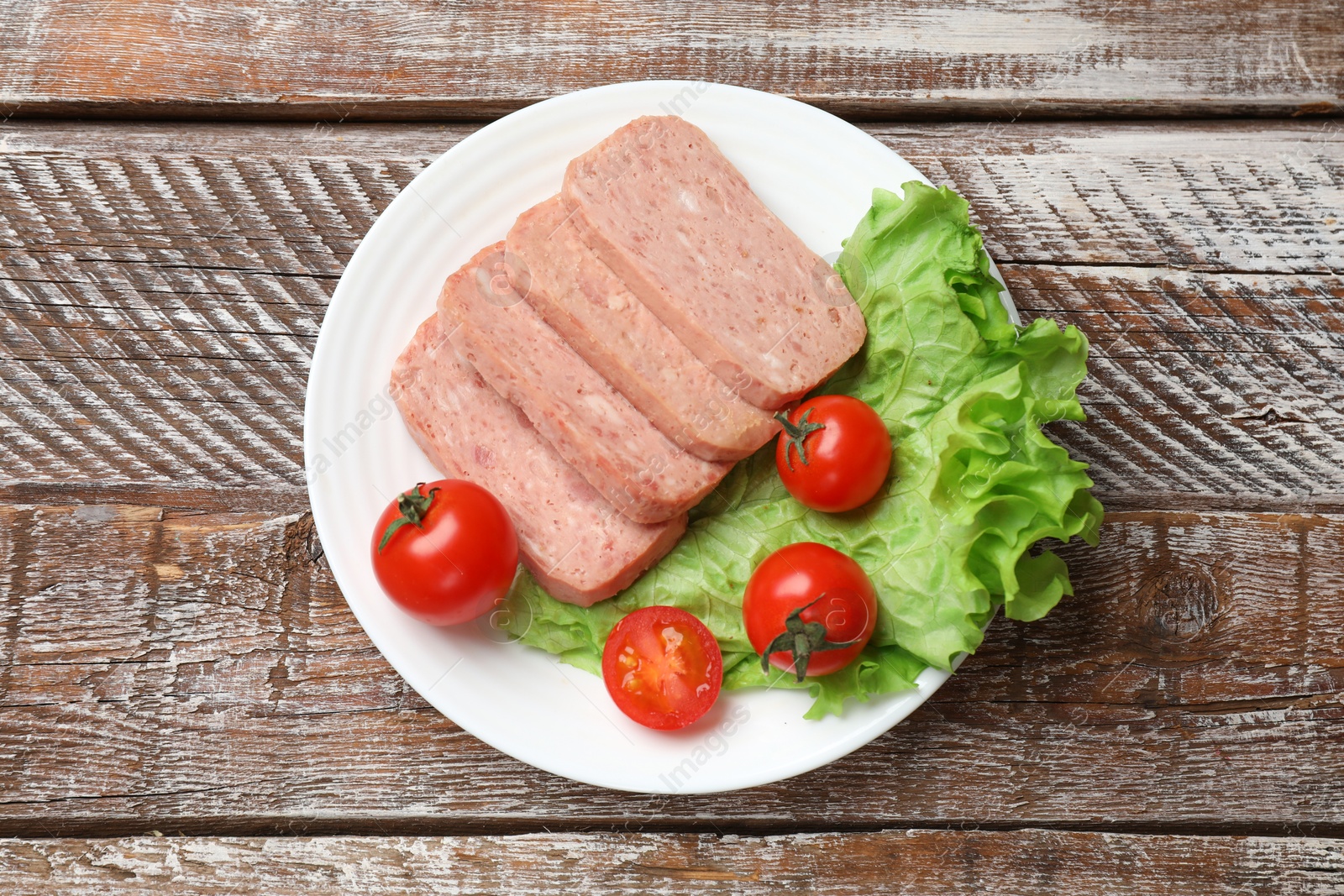 Photo of Tasty canned meat, tomatoes and lettuce on wooden table, top view