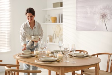 Photo of Woman setting table for dinner at home