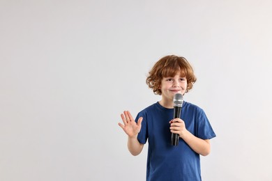 Photo of Little boy with microphone on light grey background, space for text