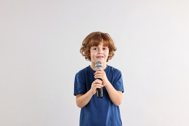 Photo of Little boy with microphone on light grey background