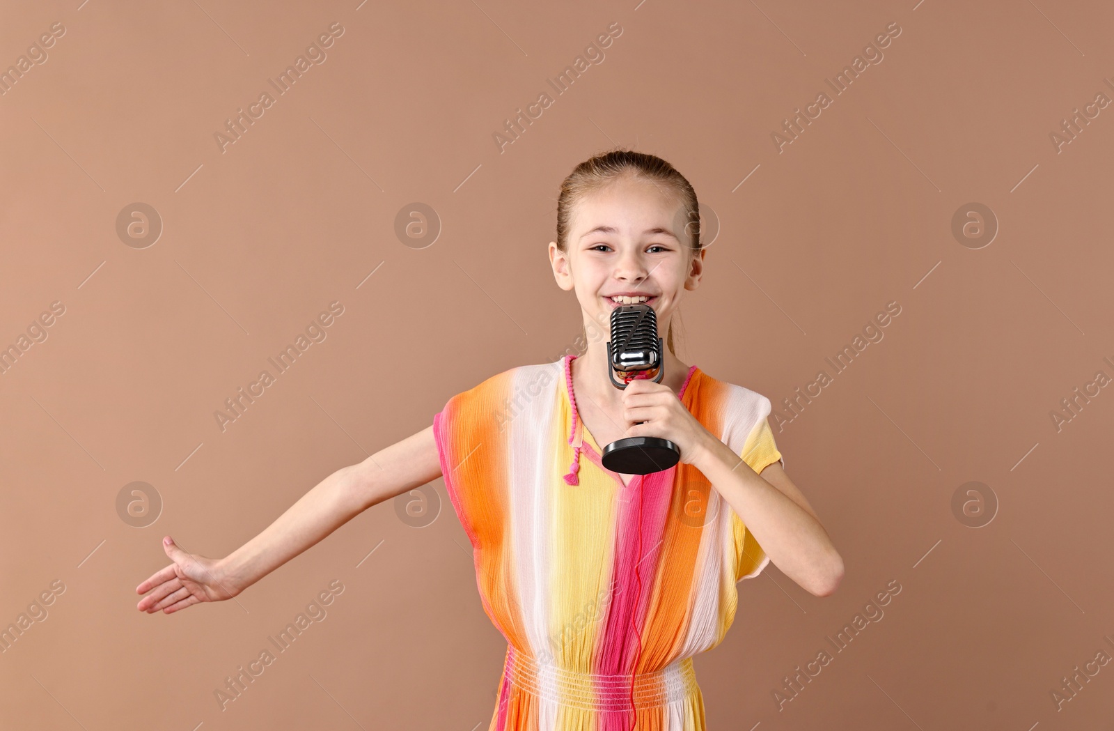 Photo of Little girl with microphone on light brown background