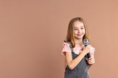 Photo of Little girl with microphone on light brown background, space for text