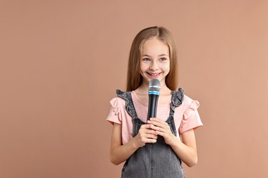 Photo of Little girl with microphone on light brown background, space for text