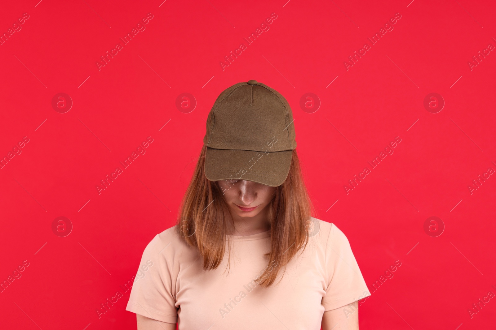 Photo of Woman in stylish baseball cap on red background. Mockup for design