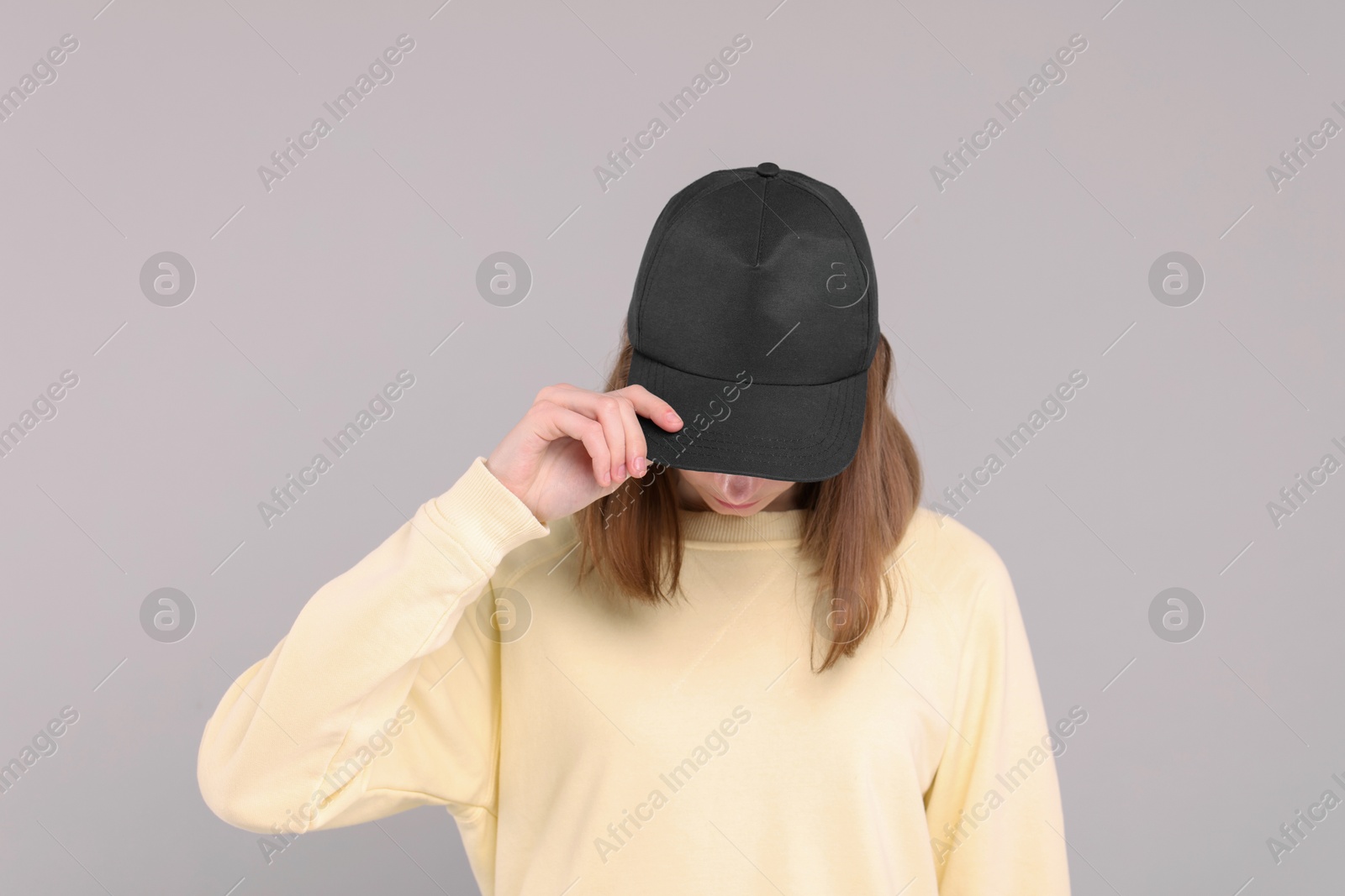 Photo of Woman in stylish baseball cap on grey background. Mockup for design