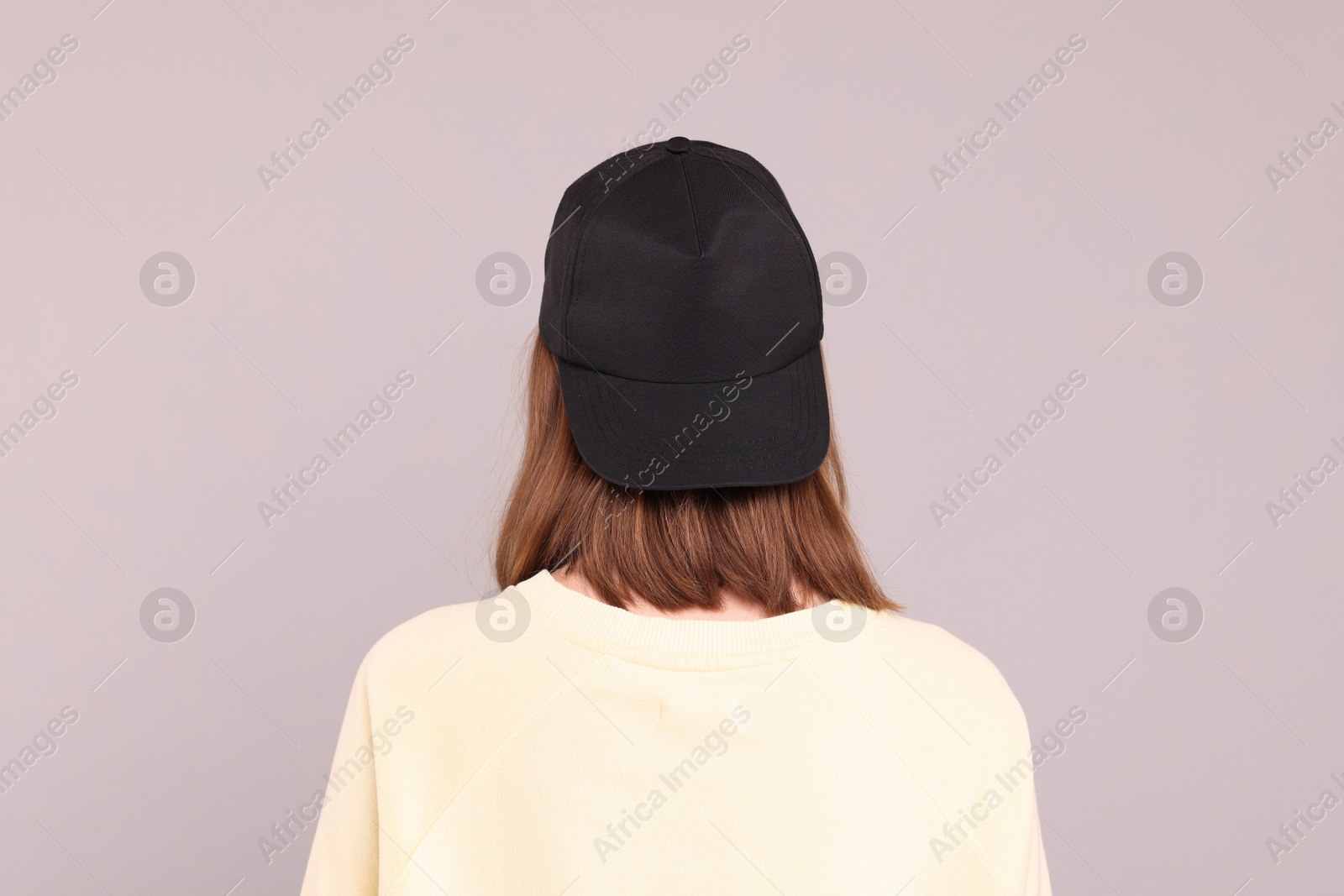 Photo of Woman in stylish baseball cap on grey background, back view. Mockup for design