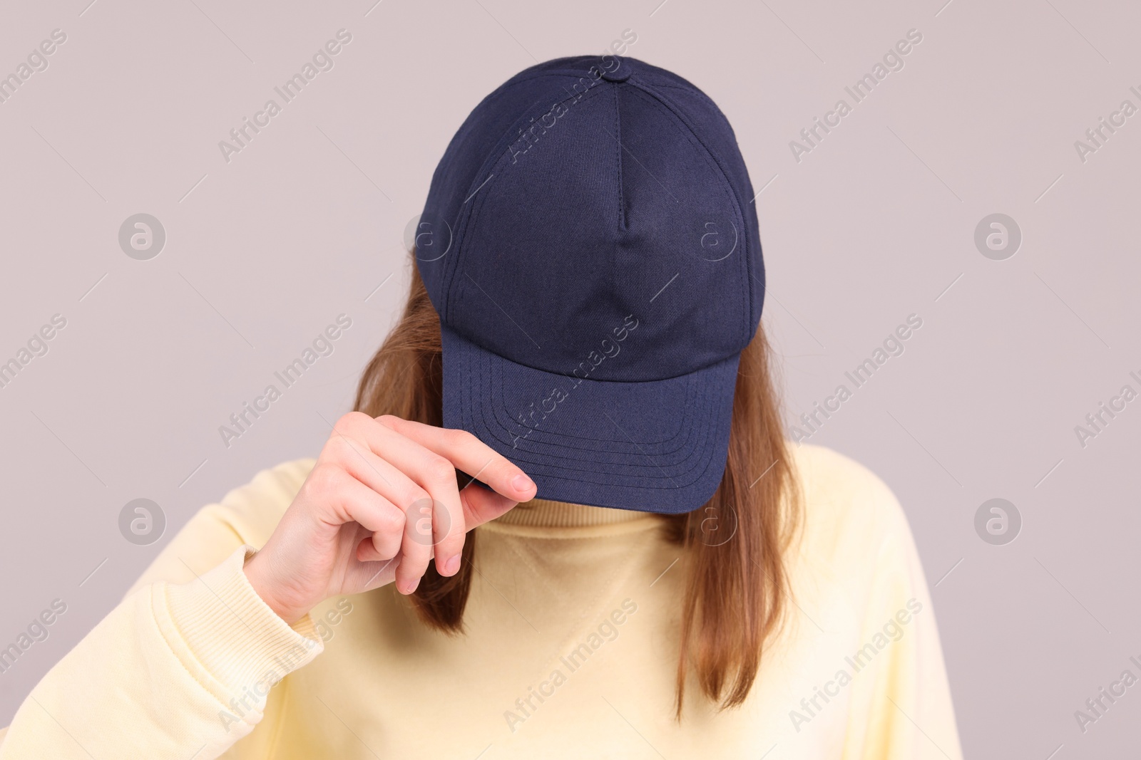 Photo of Woman in stylish baseball cap on grey background. Mockup for design