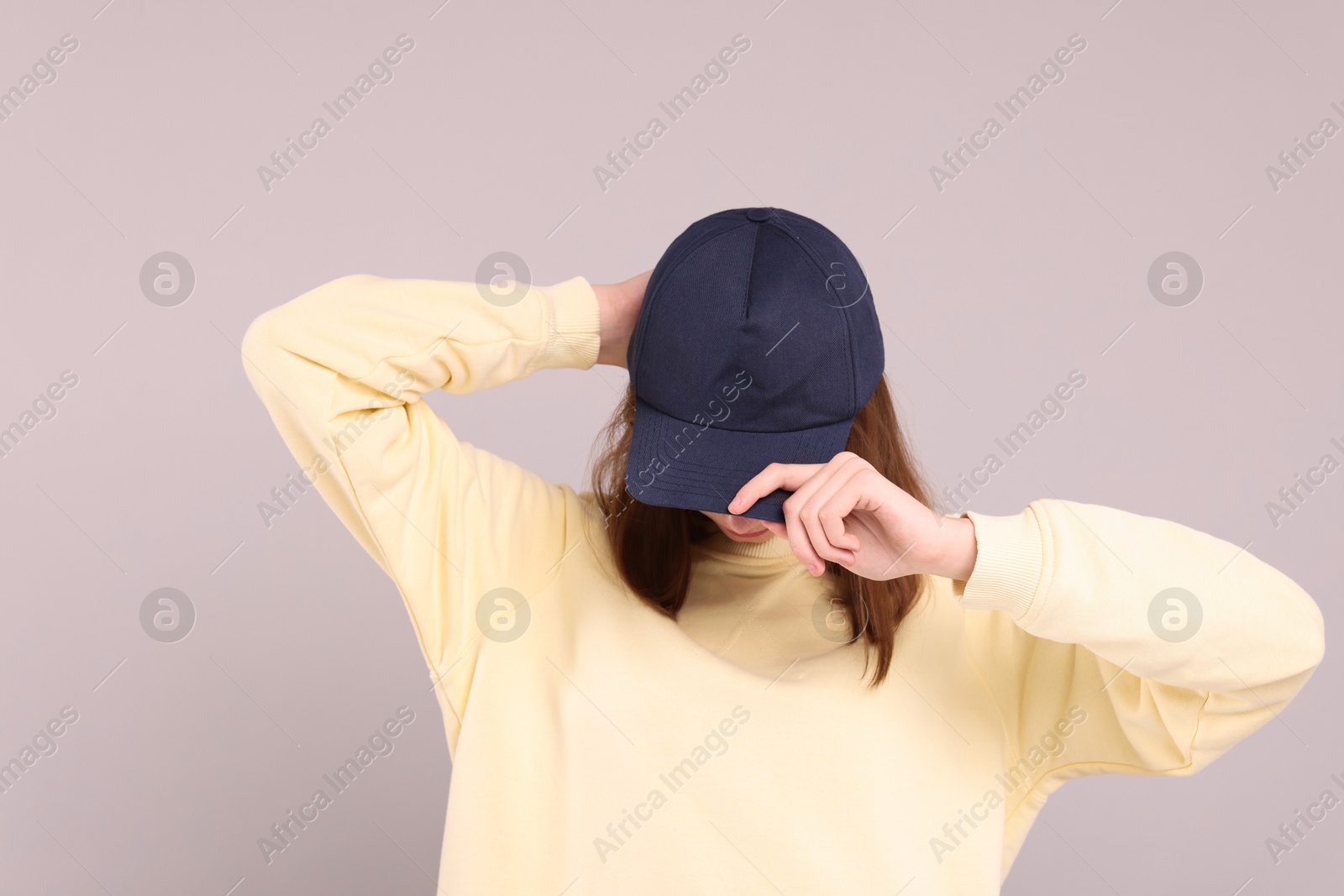 Photo of Woman in stylish baseball cap on grey background. Mockup for design