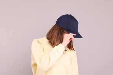 Photo of Woman in stylish baseball cap on grey background. Mockup for design