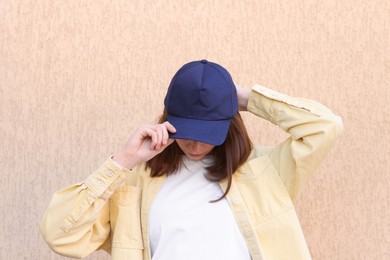 Photo of Woman in stylish baseball cap near beige wall. Mockup for design