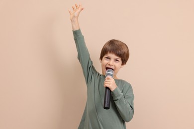 Photo of Cute boy with microphone singing near beige wall