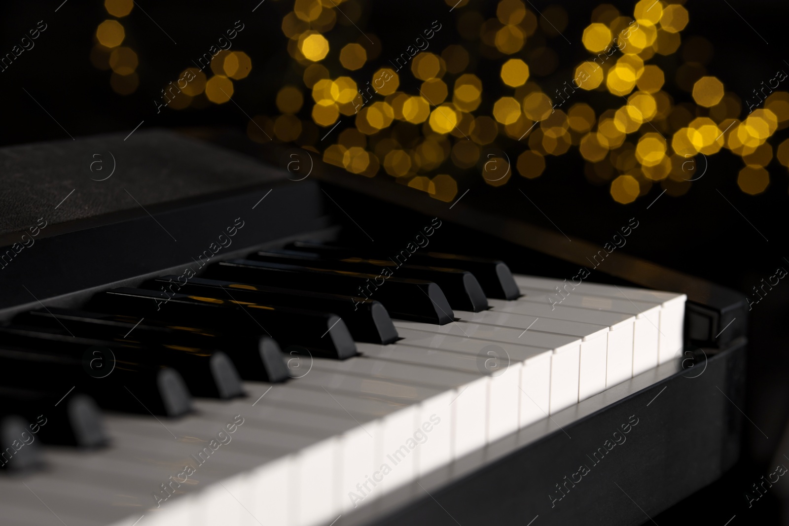 Photo of Piano against blurred lights, closeup. Bokeh effect