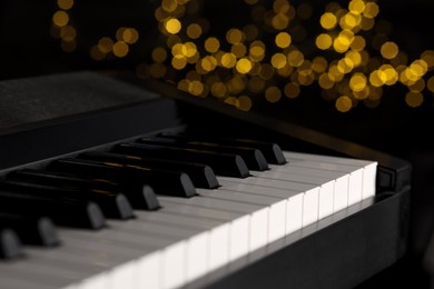 Photo of Piano against blurred lights, closeup. Bokeh effect