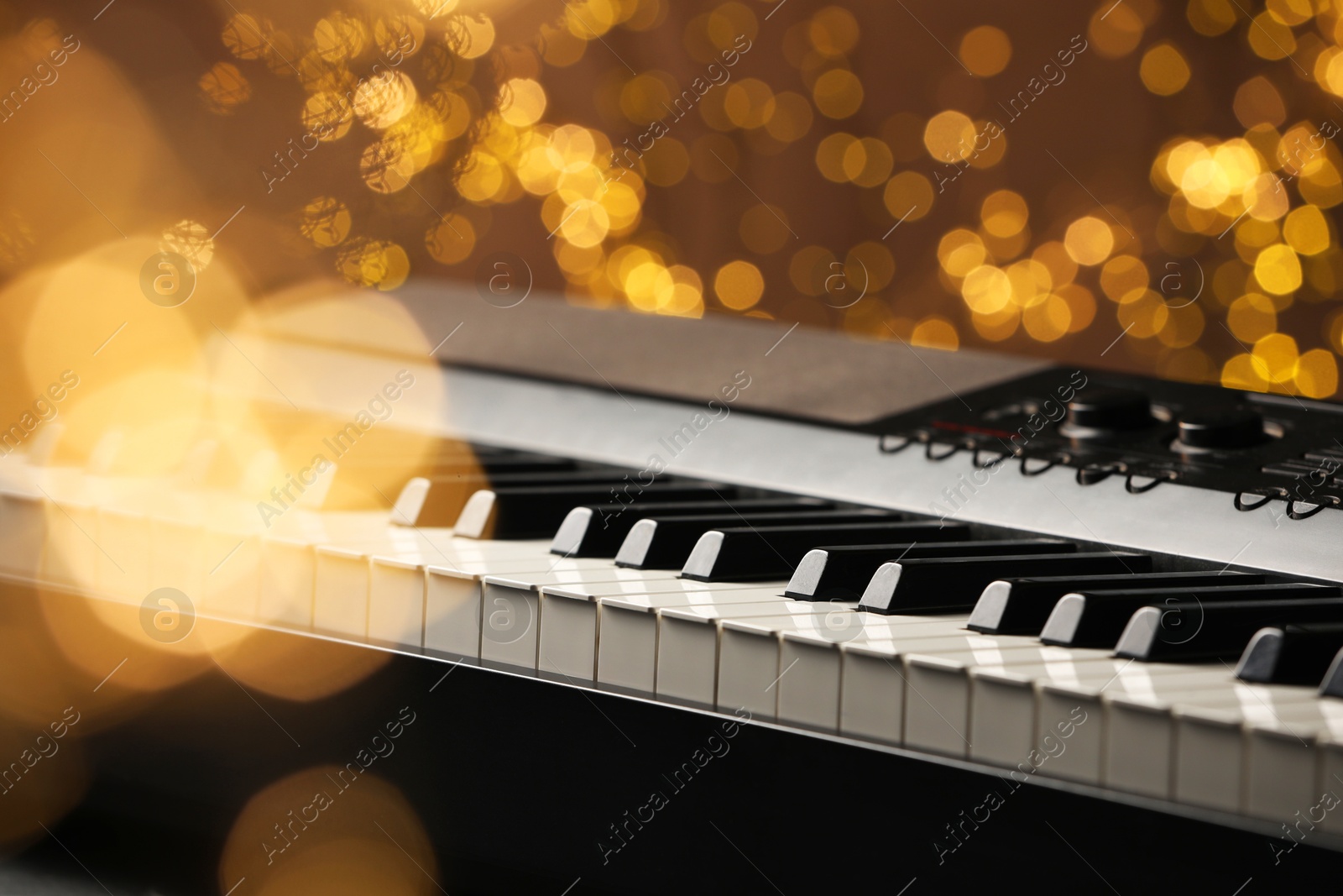 Photo of Piano against blurred lights, closeup. Bokeh effect