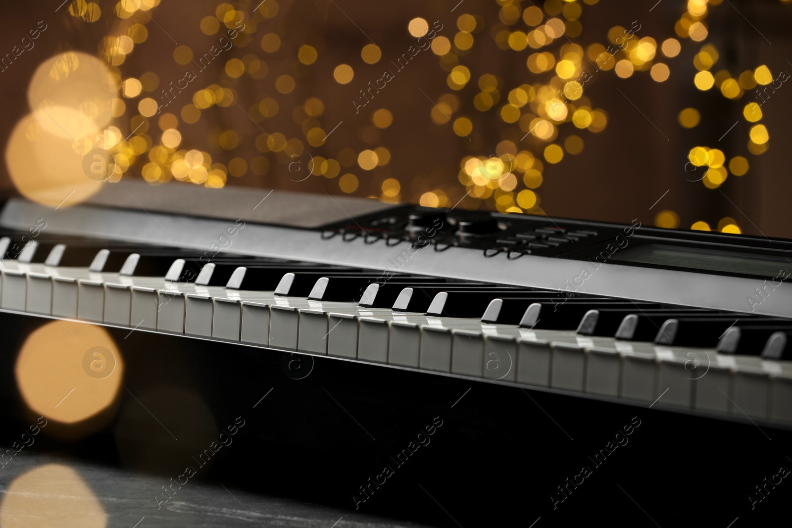 Photo of Piano against blurred lights, closeup. Bokeh effect