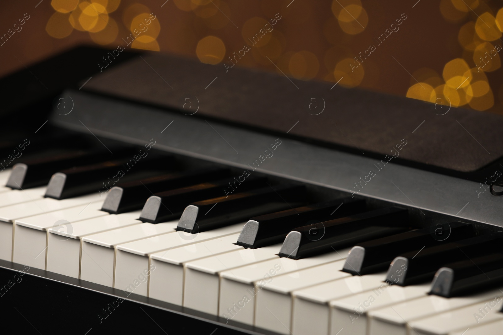 Photo of Piano against blurred lights, closeup. Bokeh effect