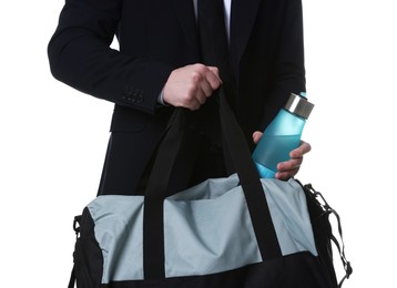 Man in suit putting bottle of water into gym bag on white background, closeup