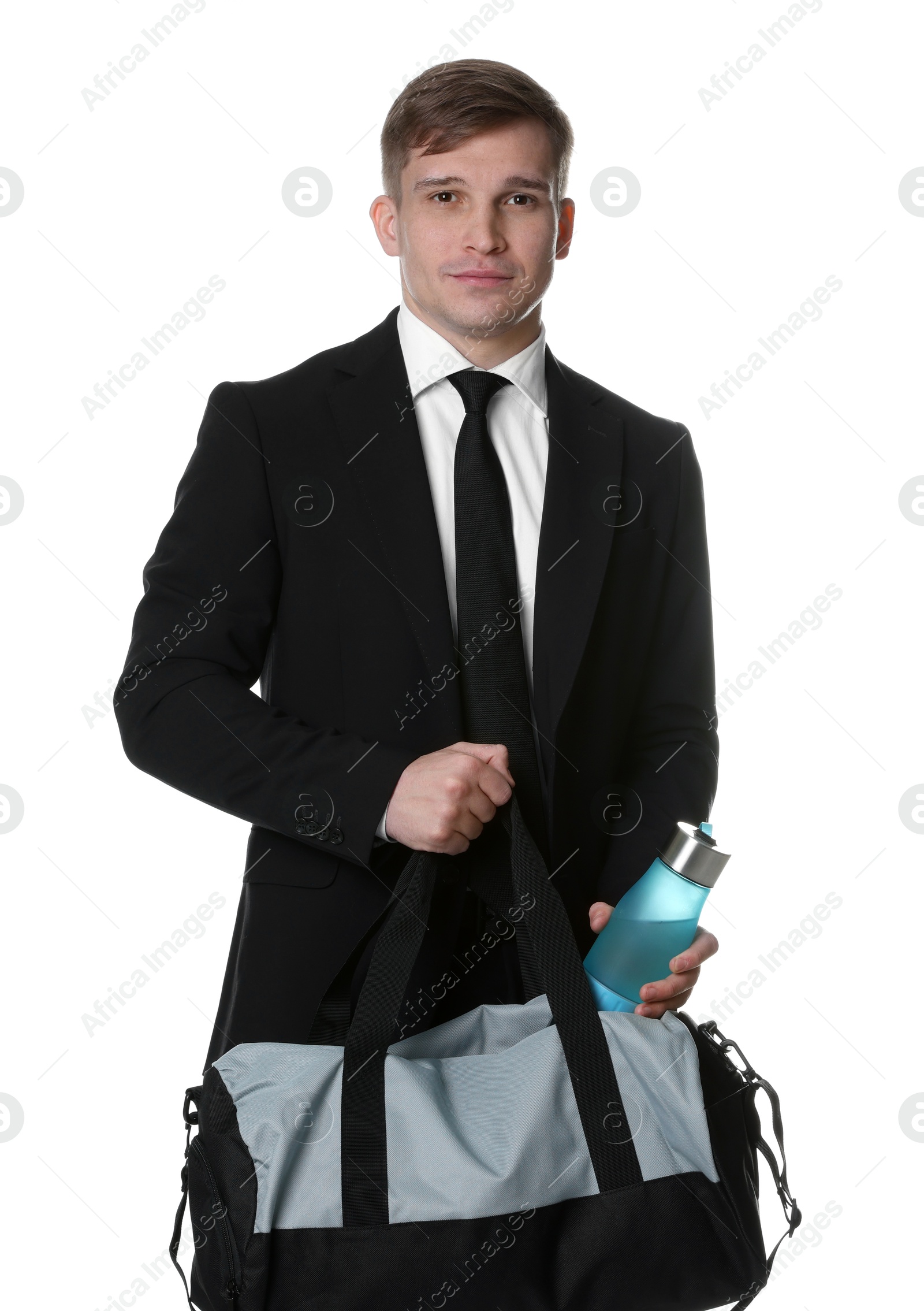 Photo of Young man in suit putting bottle of water into gym bag on white background