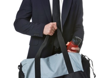 Photo of Man in suit putting bottle of water into gym bag on white background, closeup