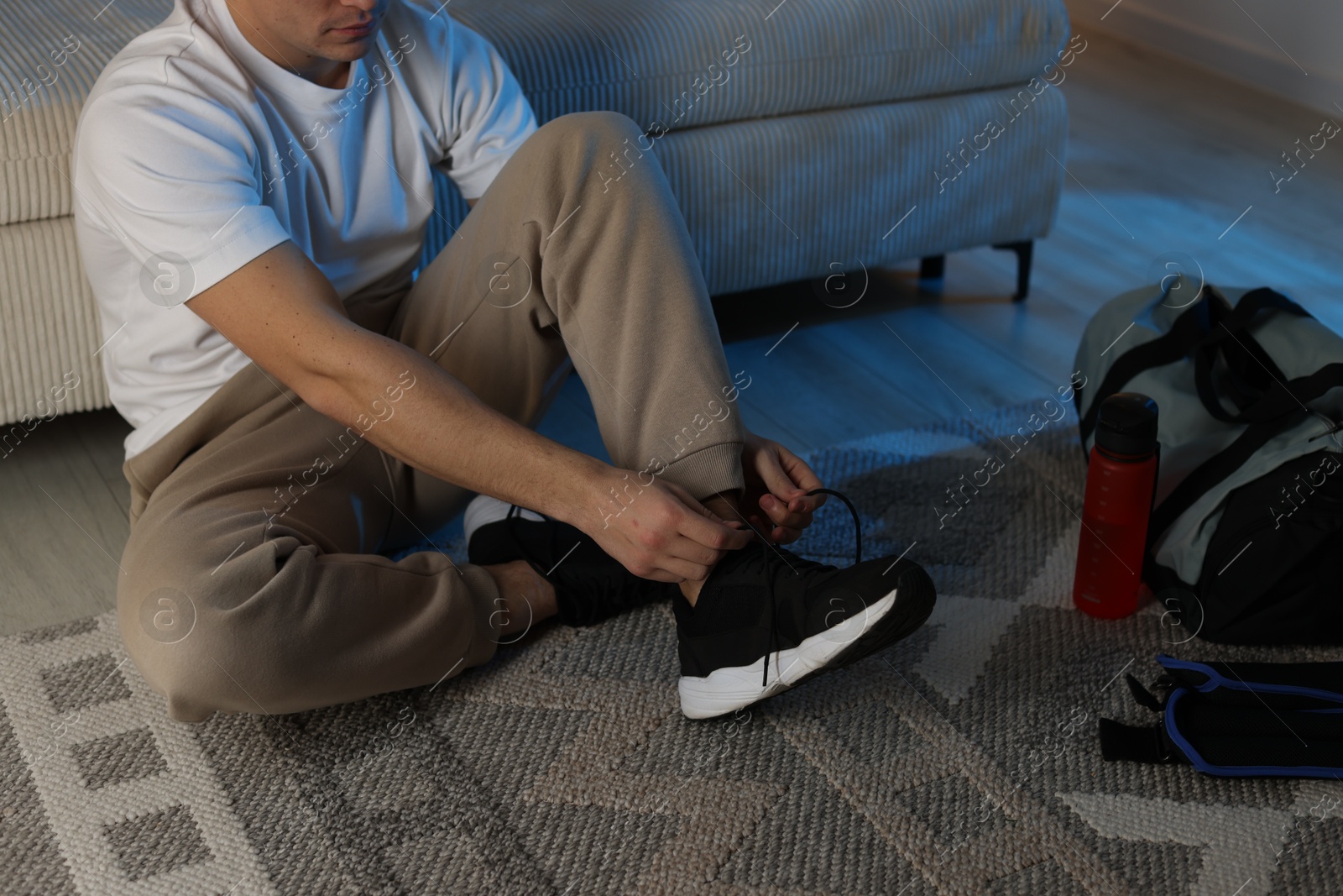 Photo of Man tying shoelace of sneaker at home, closeup