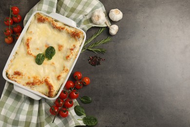 Photo of Delicious spinach lasagna in baking dish and ingredients on grey table, flat lay. Space for text