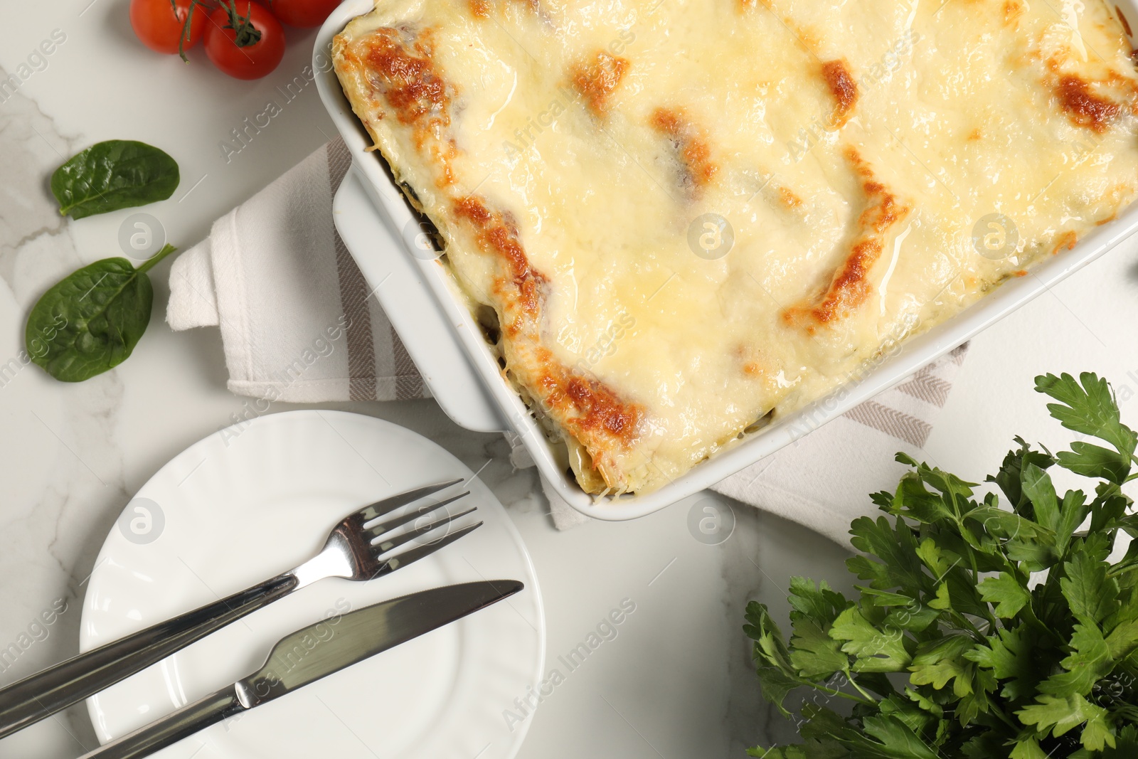 Photo of Delicious spinach lasagna in baking dish served on white table, flat lay