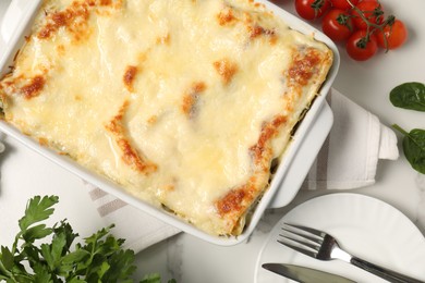 Photo of Delicious spinach lasagna in baking dish served on white table, flat lay