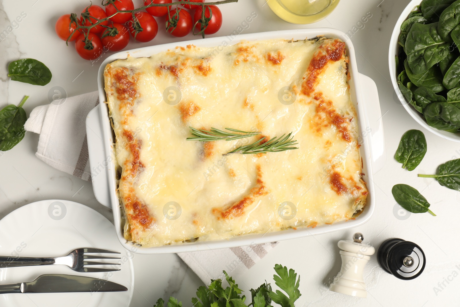 Photo of Delicious spinach lasagna in baking dish served on white table, flat lay