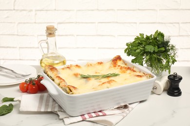 Photo of Delicious spinach lasagne in baking dish and ingredients on grey marble table