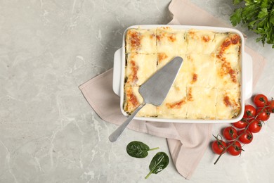 Photo of Delicious spinach lasagne in baking dish served on grey marble table, flat lay. Space for text