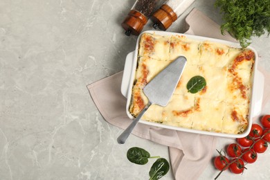 Photo of Delicious spinach lasagne in baking dish served on grey marble table, flat lay. Space for text