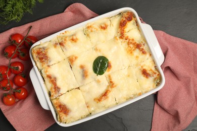 Photo of Delicious spinach lasagne in baking dish and ingredients on grey table, top view