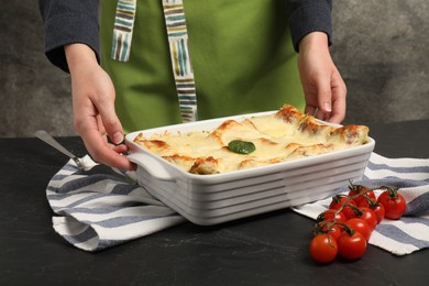 Photo of Woman with delicious spinach lasagne at grey table, closeup