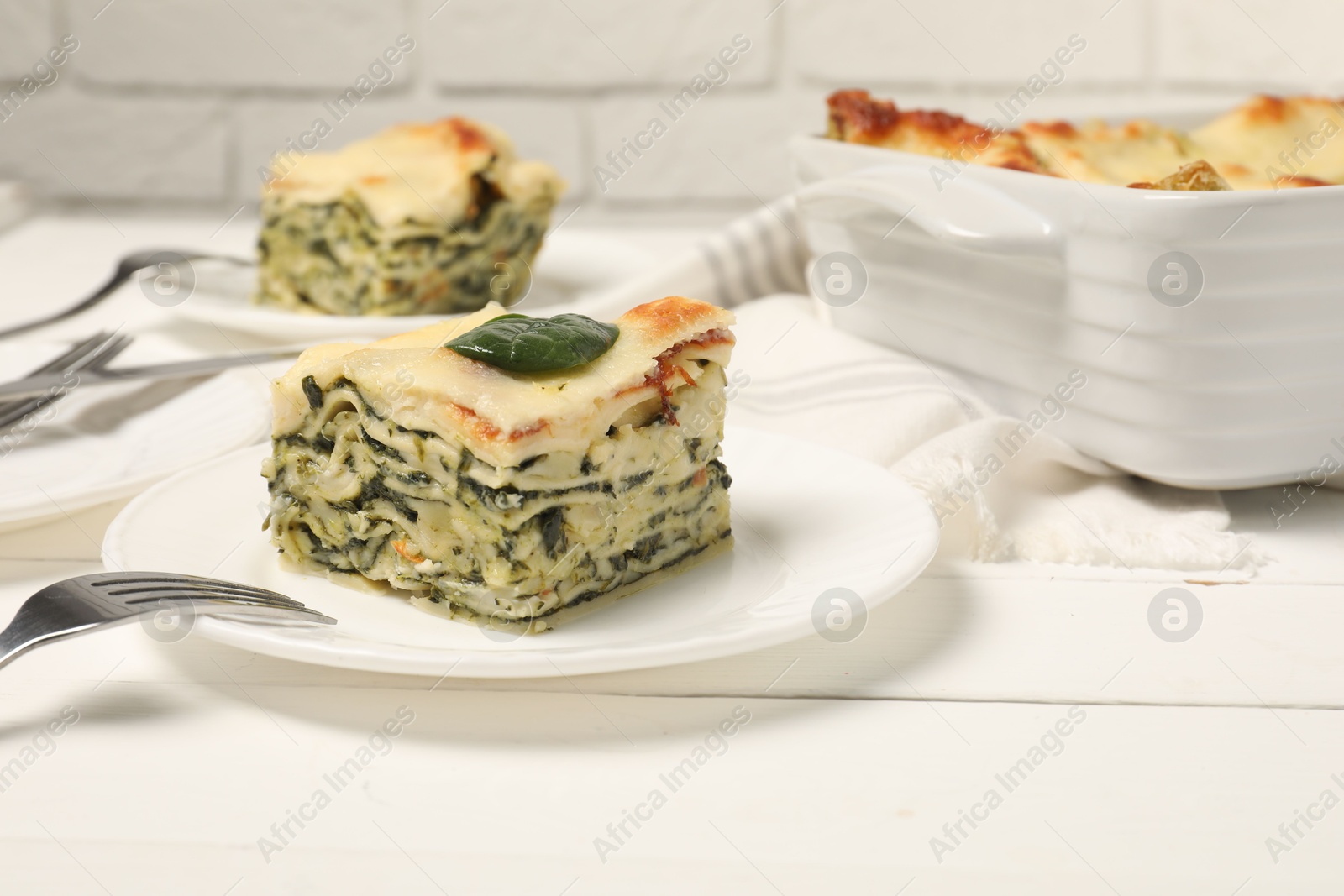 Photo of Delicious spinach lasagne served on white wooden table