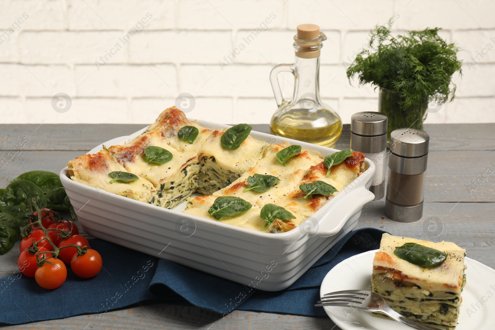 Photo of Delicious spinach lasagne and ingredients on grey wooden table