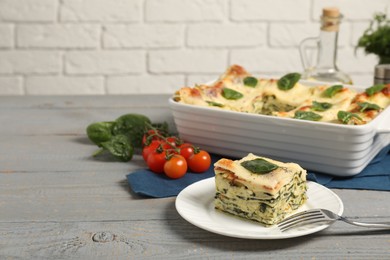 Photo of Delicious spinach lasagne on grey wooden table, space for text