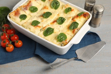 Photo of Delicious spinach lasagne in baking dish served on grey wooden table