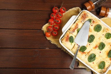 Photo of Delicious spinach lasagne in baking dish served on wooden table, flat lay. Space for text