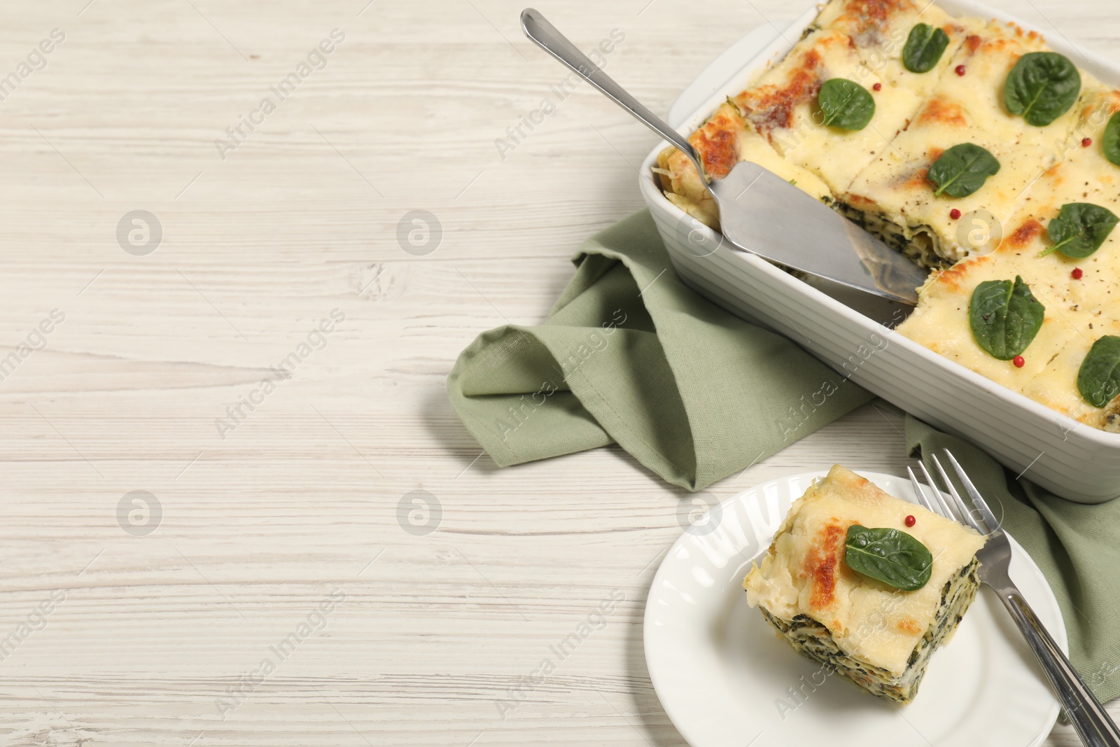 Photo of Delicious spinach lasagne served on white wooden table, space for text